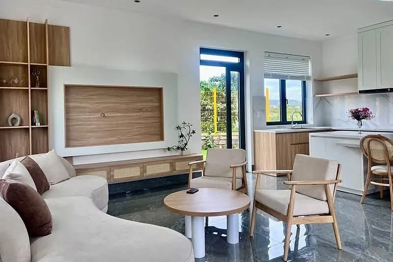 Phòng khách thông bếp căn biệt thự – nội thất gỗ tự nhiên, sofa, bàn ăn, cửa kính lớn nhìn ra vườn