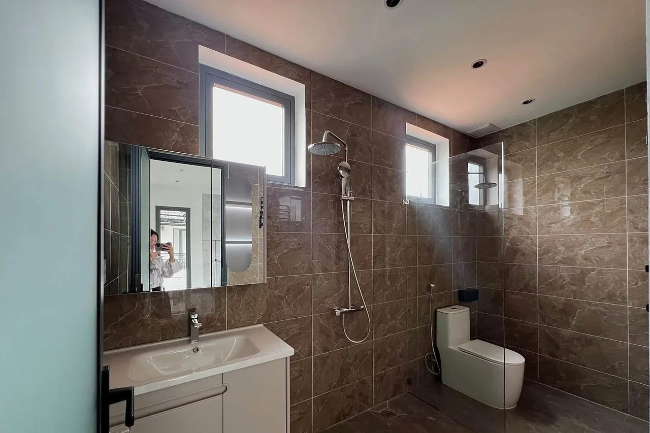 Phòng tắm ốp đá – vòi sen cây, lavabo, bồn cầu, cửa kính, sạch sẽ hiện đại