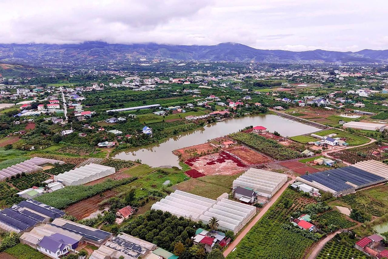 Ảnh flycam khu 4 lô gần hồ Từ Liêm, Nam Ban: hồ nước phía sau, vườn và nhà kính xung quanh, núi phía xa
