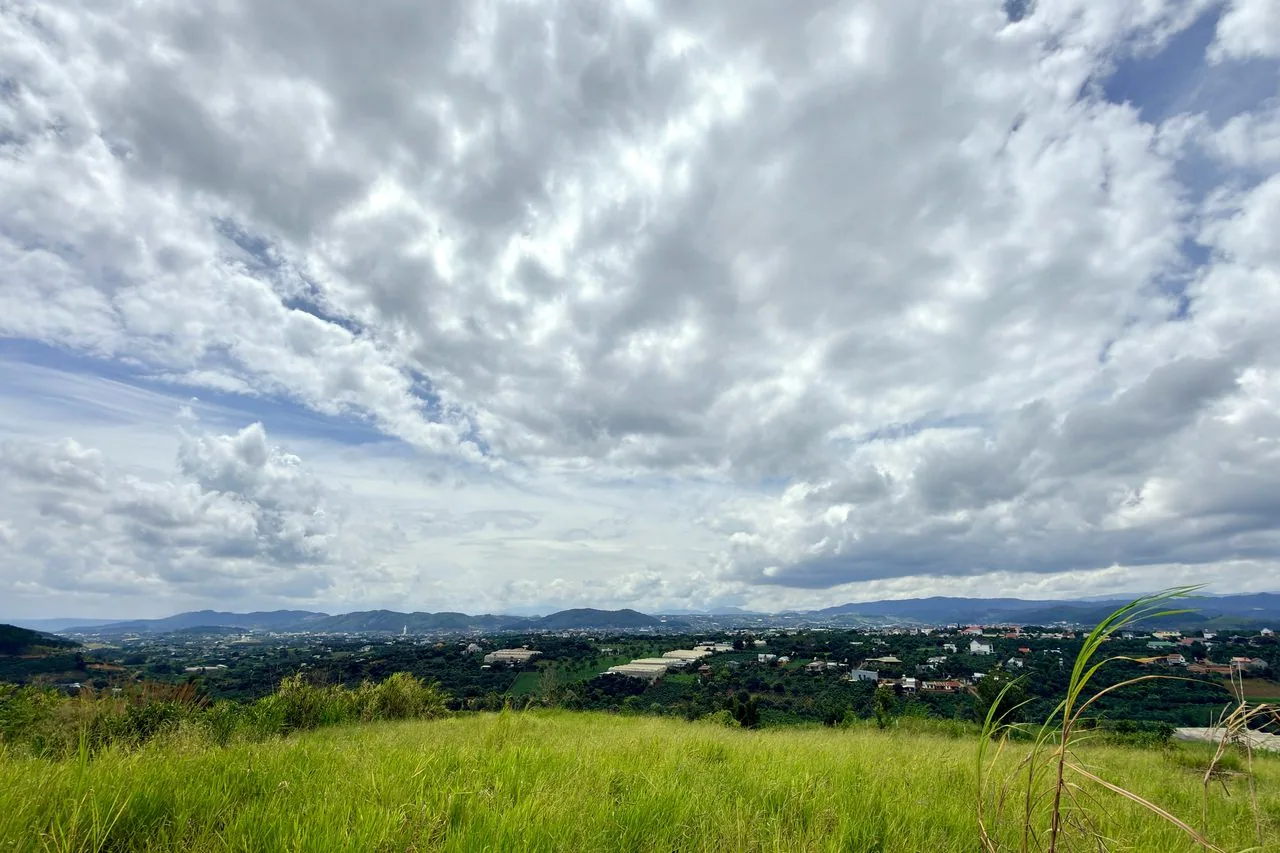 View toàn cảnh thị trấn và thung lũng Đông Thanh Nam Ban từ khu đất Golden View, đồng cỏ xanh tiền cảnh, mây trời, ven Đà Lạt