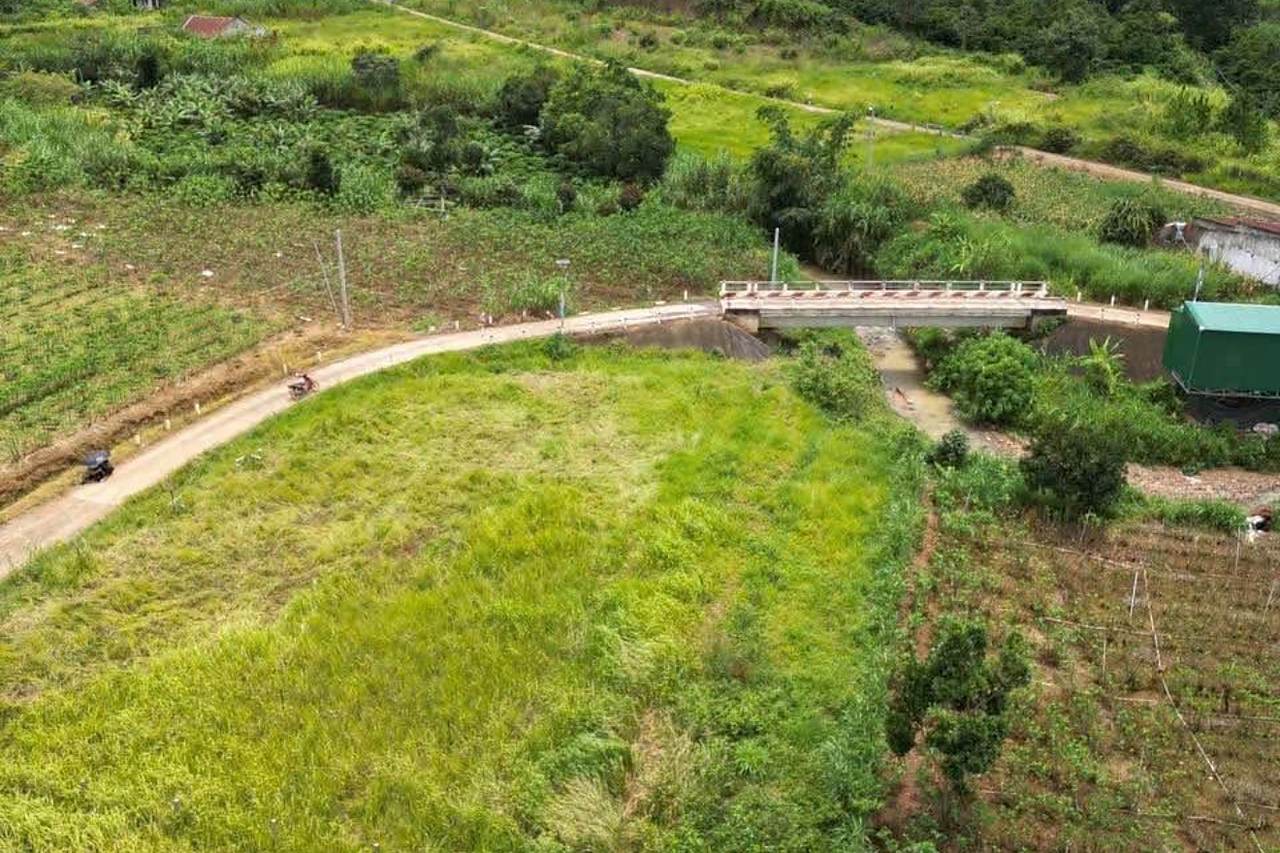 Lô đất giáp suối Nam Ban nhìn từ phía cầu – đường xe hơi uốn quanh lô, vườn và nhà dân xung quanh