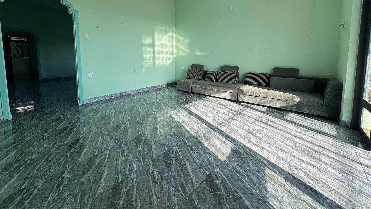Phòng khách nhà cấp 4 rộng rãi, nền lát gạch bóng, thông sang phòng trong