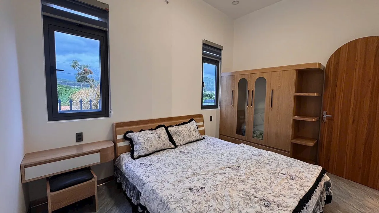 Phòng ngủ nội thất gỗ tự nhiên, cửa sổ view đồi – nhà gần hồ Bãi Công