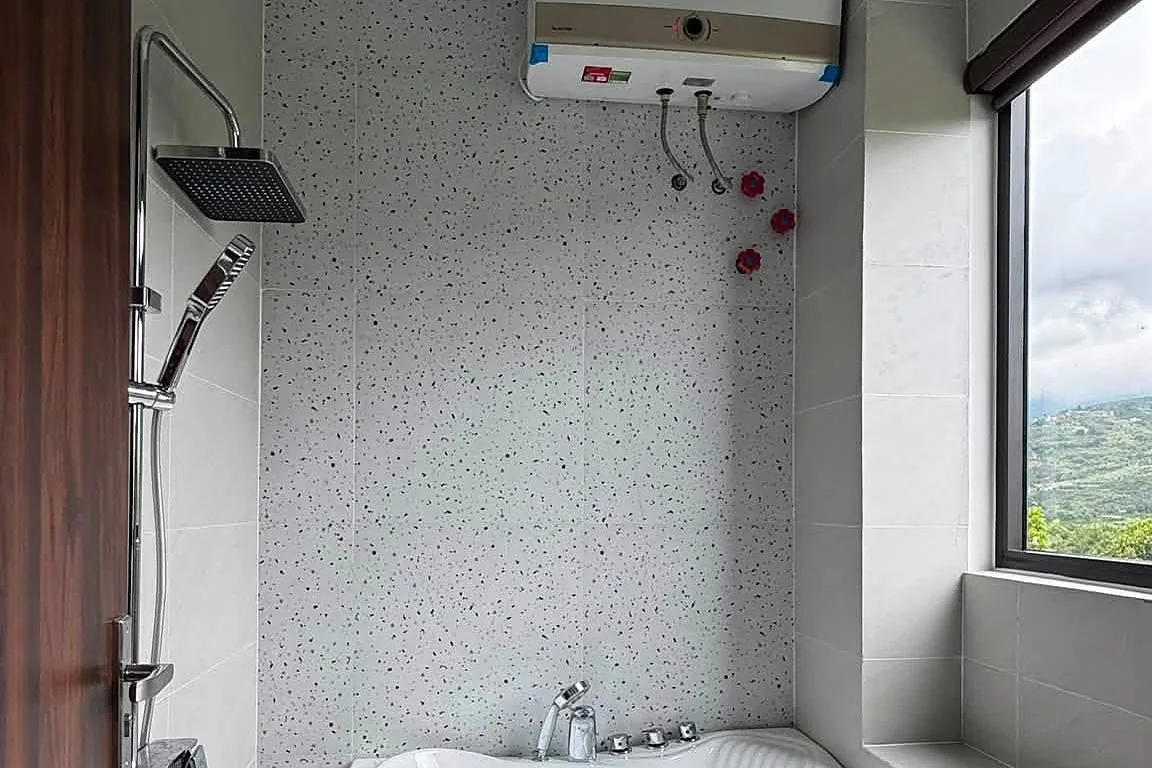 Phòng tắm bồn góc jacuzzi, cửa sổ nhìn ra đồi núi Nam Ban