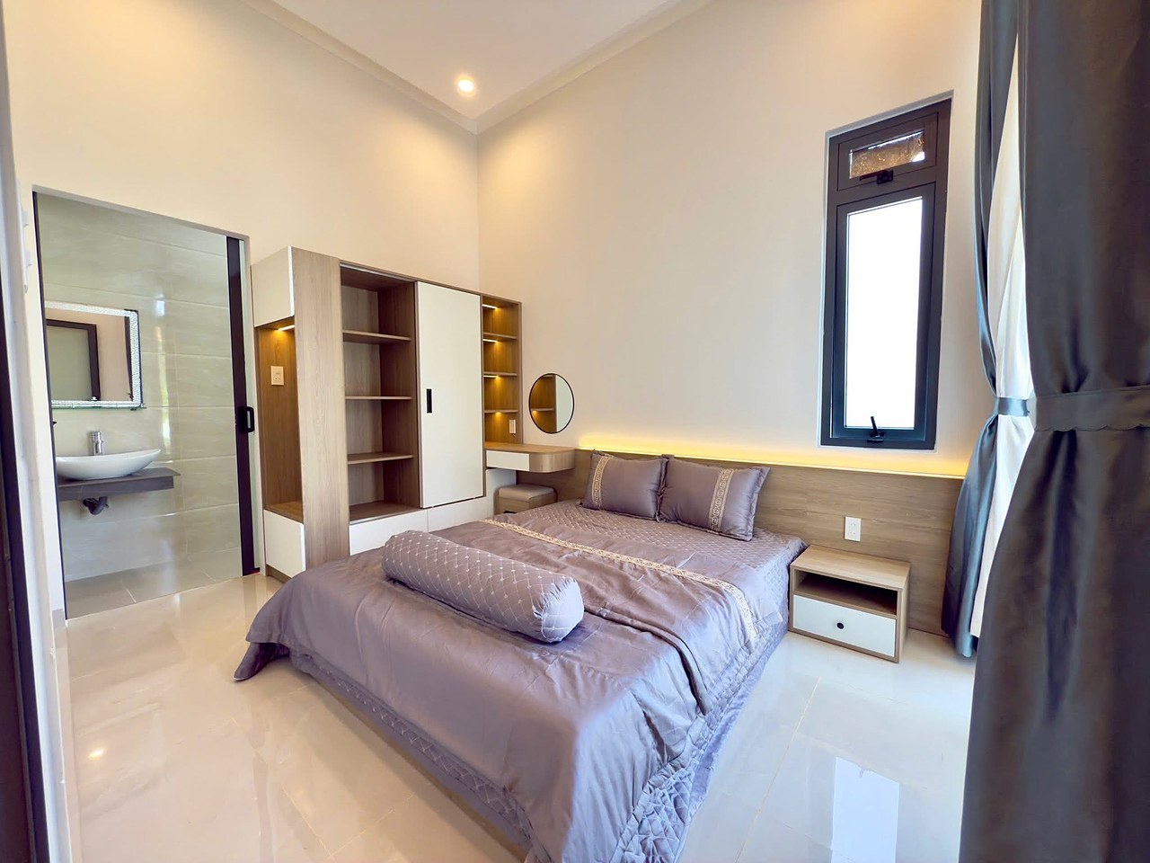 Phòng ngủ 2 có WC riêng — giường đôi, tủ kệ gỗ, cửa sổ đứng, chậu rửa và gương