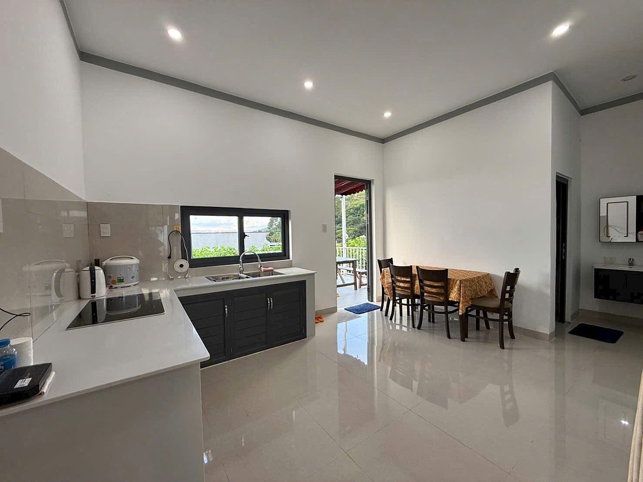 Bếp mở ra bàn ăn và phòng khách, bàn đá trắng, cửa ra ban công