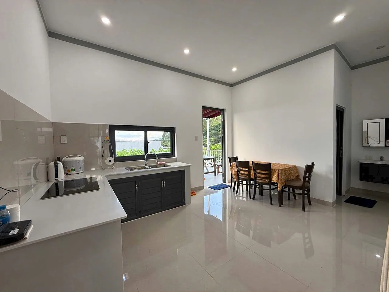 Bếp mở ra bàn ăn và phòng khách, bàn đá trắng, cửa ra ban công