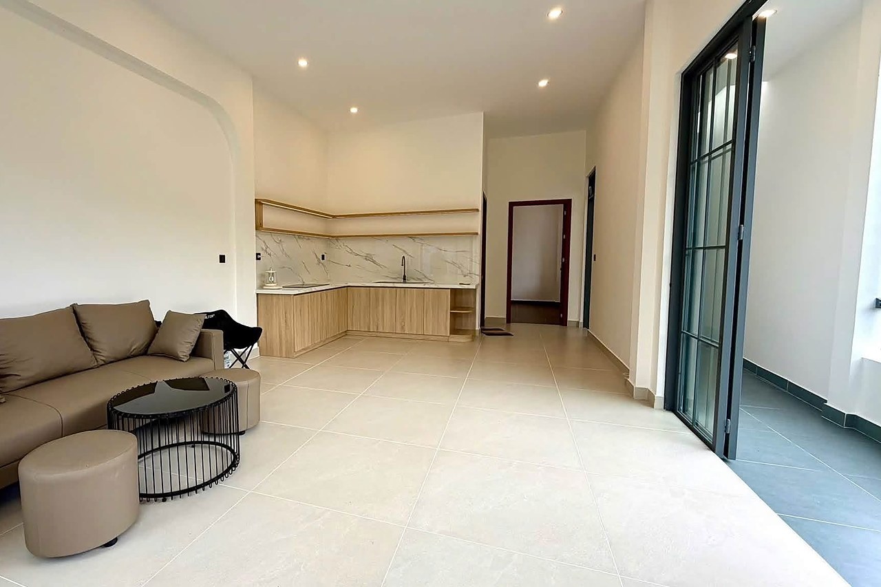 Phòng khách liên thông bếp, full nội thất, sofa và tủ bếp gỗ, cửa kính ra sân