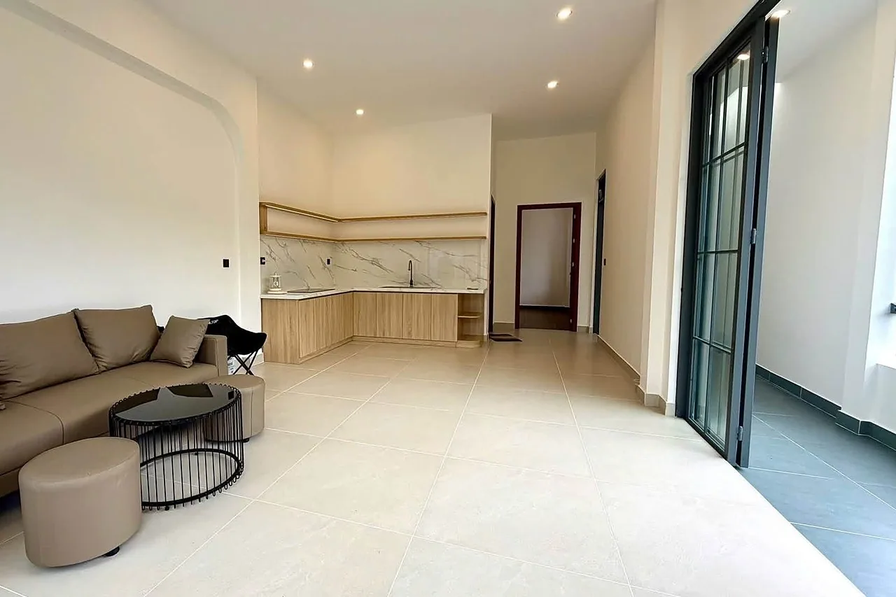Phòng khách liên thông bếp, full nội thất, sofa và tủ bếp gỗ, cửa kính ra sân