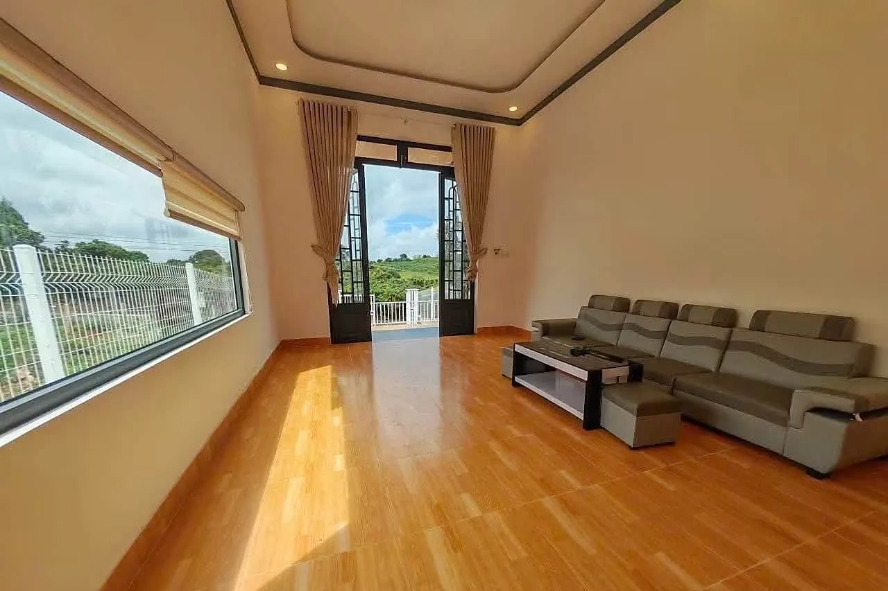 Phòng khách nhà vườn Nam Ban – sàn gạch vân gỗ, sofa, cửa kính lớn nhìn ra vườn và đồi, đủ nội thất cơ bản