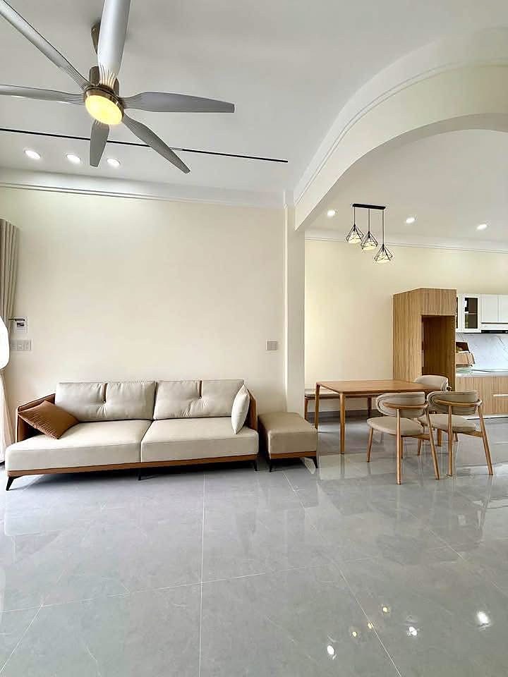 Phòng khách liền bếp và bàn ăn, sofa kem, gạch bóng
