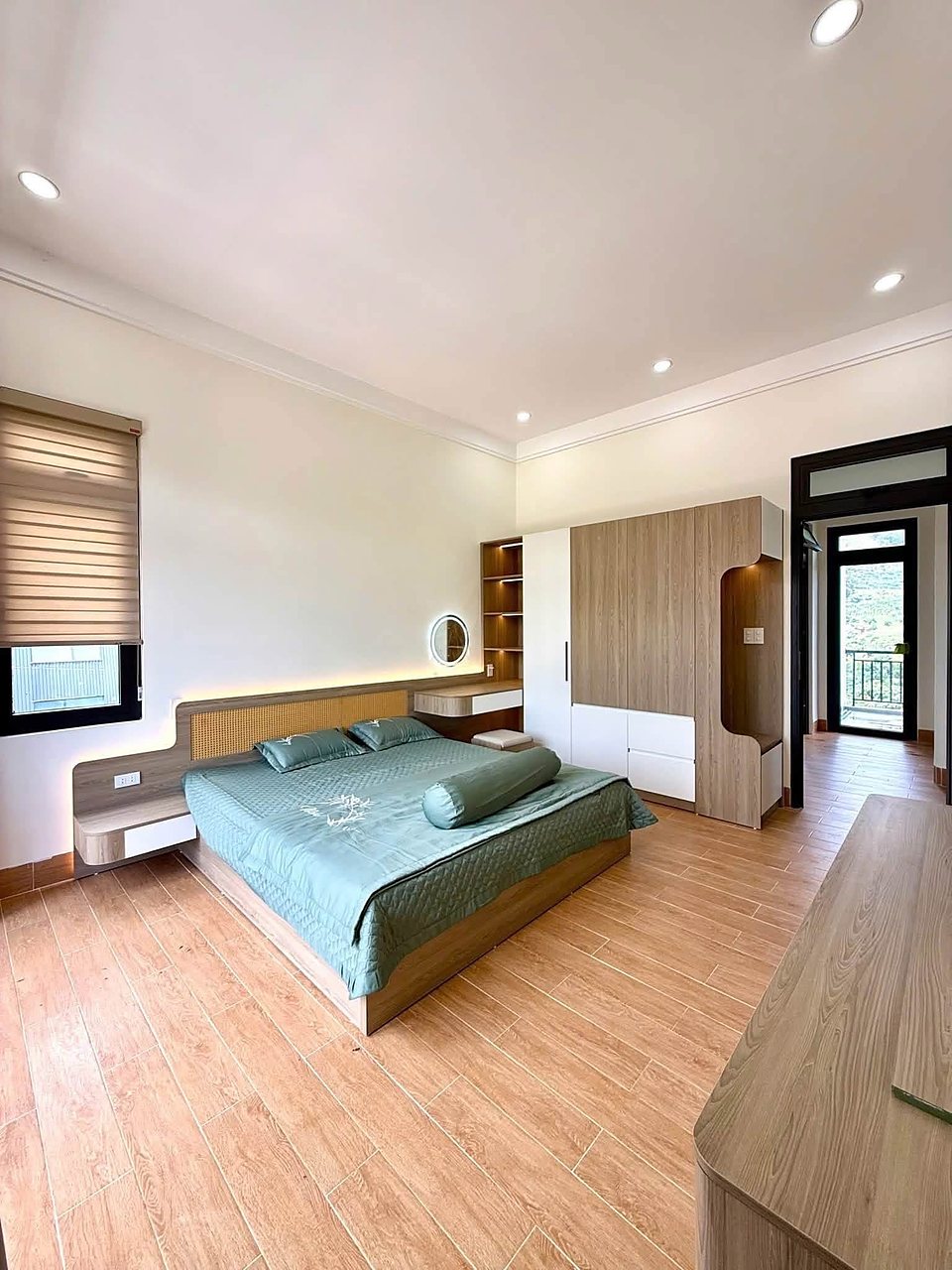 Phòng ngủ giường xanh, tủ gỗ, cửa ra ban công