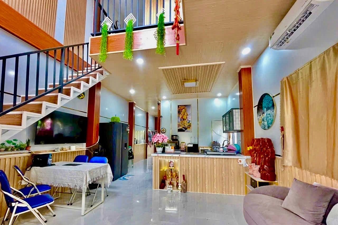 Phòng khách liền bếp có gác lửng, nội thất gọn gàng, đèn ấm