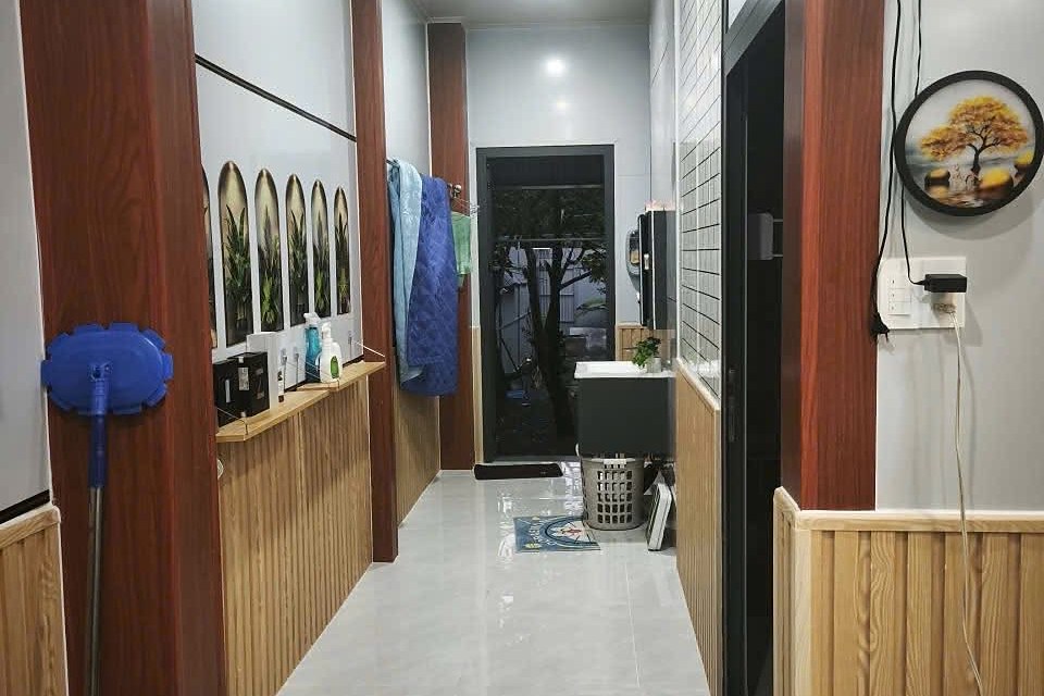 Hành lang trong nhà lát gạch sáng, dẫn ra khu vệ sinh và sân sau