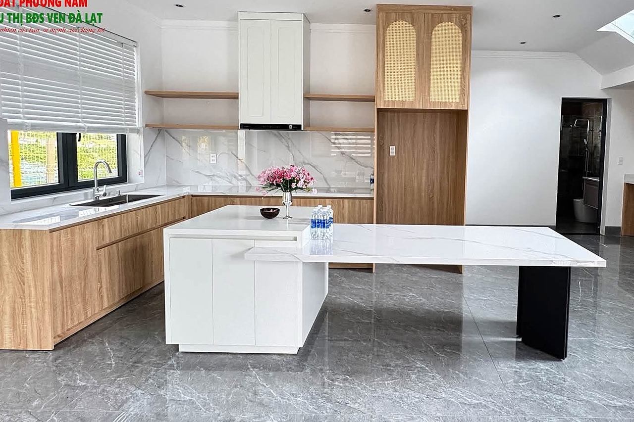 Bếp hiện đại bàn đảo đá marble, tủ bếp gỗ, cầu thang kính lên gác