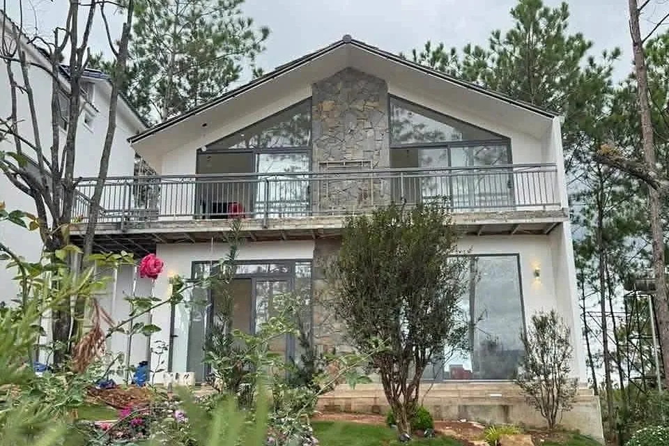 Villa 2 tầng đá ốp giữa rừng thông HT86 Nam Ban – gable kính lớn, ban công, vườn hoa hồng