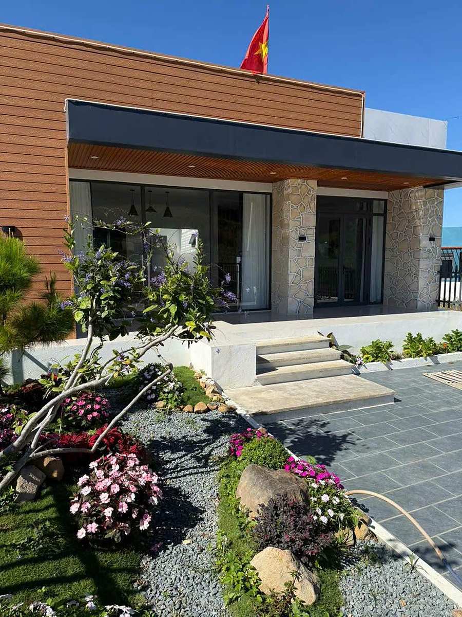Mặt tiền villa Nam Ban ốp gỗ và đá, hiên kính lớn, sân vườn hoa cẩm tú cầu và sỏi đá