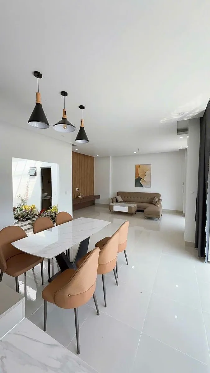 Phòng khách liền bàn ăn villa Nam Ban, bàn đá marble, ghế bọc nệm, sàn gạch bóng sáng